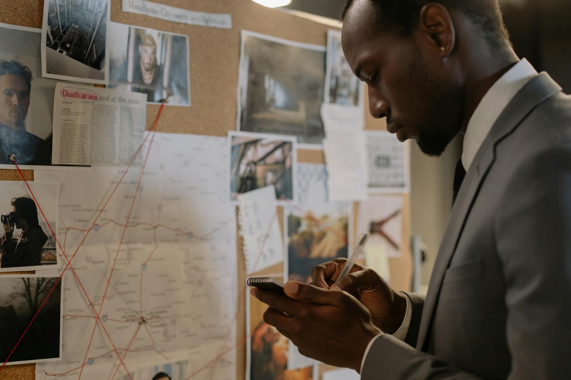 Man in a suit investigating a crime scene board, taking notes and analyzing evidence.